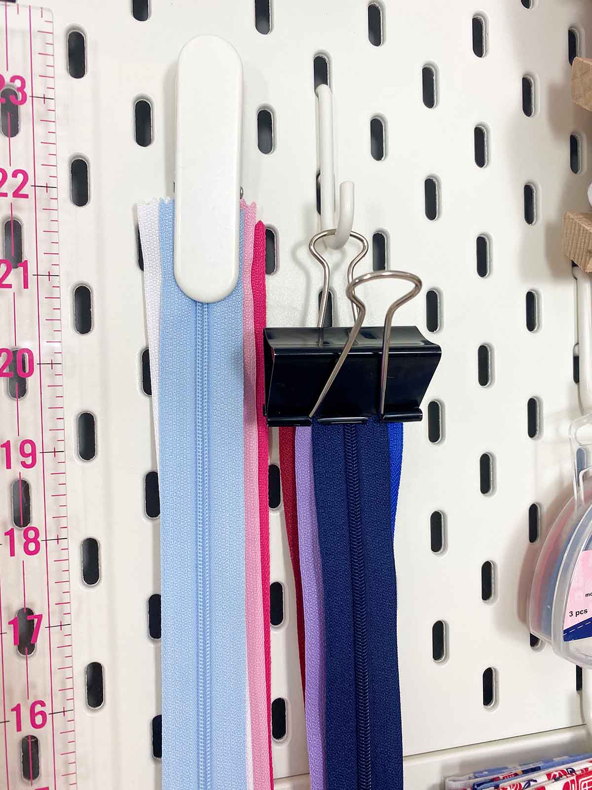 Hang zips on a sewing pegboard from clips. If you do not have any Ikea pegboard clips you can use bull dog clips on a hook.